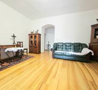 Obývací pokoj v 3-pokojovém bytě s podlahou s dřevěným dekorem, pohovkou a dřevěným nábytkem.