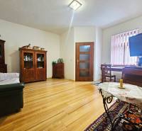 Obývací pokoj v 3-pokojovém bytě s podlahou s dřevěným dekorem a nábytkem z tmavého dřeva.