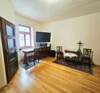 Pokoj v 3-pokojovém bytě s podlahou s dřevěným dekorem a televizí na stolku.