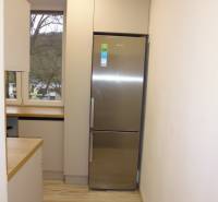 Kuchyně s podlahou s dřevěným dekorem a lednicí v 2pokojovém bytě.