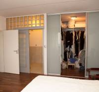 Ložnice v rodinném domě s posuvnými dveřmi a šatníkem, podlaha s dřevěným dekorem.