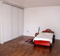 Dětský pokoj v rodinném domě s postelí ve tvaru auta a podlahou s dřevěným dekorem.