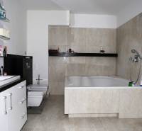 Koupelna s velkou vanou a světlými obklady v rodinném domě.