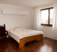 Ložnice v rodinném domě s postelí, křeslem a podlahou s dřevěným dekorem.