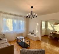 Obývací pokoj ve 3-pokojovém bytě s podlahou s dřevěným dekorem a prostorným oknem.