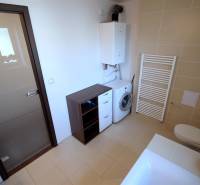 Koupelna s vanou, umyvadlem, pračkou a skříňkami v 2-pokojovém bytě.