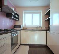 Kuchyně v 2pokojovém bytě s plynovým sporákem a podlahou s dřevěným dekorem.