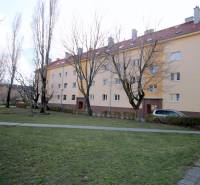 Bytový dům na Kadnárově ulici v Bratislavě - Rači obklopený zelení a chodníkem.