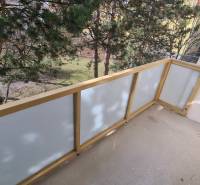 Balkon 2-pokojového bytu s výhledem na zeleň, s průhledným zábradlím.