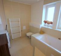 Koupelna s vanou, dlažbou a pračkou v 2-pokojovém bytě.