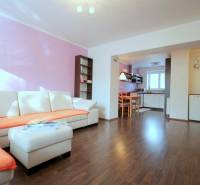 Obývací pokoj v 2-pokojovém bytě s rohovou sedačkou a podlahou s dřevěným dekorem.