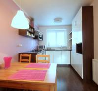 Kuchyně v 2-pokojovém bytě s podlahou s dřevěným dekorem a růžovými doplňky.