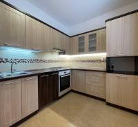 Kuchyně v 2pokojovém bytě s podlahou s dřevěným dekorem a světlým nábytkem.