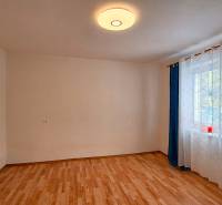 Pokoj v rodinném domě s podlahou s dřevěným dekorem a závěsy u okna.