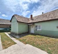 Rodinný dům v Hajnáčce s asfaltovým chodníkem a zeleným trávníkem pod modrou oblohou.