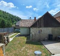 Rodinný dům v Hajnáčce s oploceným dvorem, dřevěnou přístavbou a uskladněným dřevem.