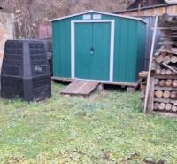 Rodinný dům v Hajnáčce se zeleným zahradním domkem, kompostérem a skladem dřeva.