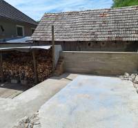 Dvůr rodinného domu v Hajnáčce s dřevníkem a betonovou plochou.