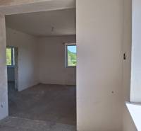 Interiér rodinného domu s nedokončenými stěnami a betonovou podlahou.