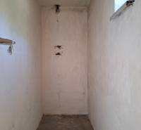 Úzký interiérový prostor v rodinném domě s malým oknem a betonovou podlahou.