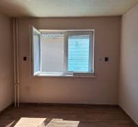 Pokoj v rodinném domě s otevřeným oknem a podlahou s dřevěným dekorem.