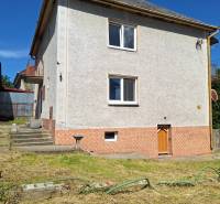 Rodinný dům v Šíde se strmou střechou a upravenou zahradou s trávníkem.