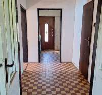 Chodba v rodinném domě s dlažbou a dveřmi.