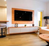 Obývací pokoj v 3-pokojovém bytě s podlahou s dřevěným dekorem, televizorem a krémovými sedačkami.