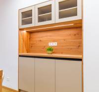 Kuchyňská linka s horními skříňkami, dřevěný dekor a rostlina v 3-pokojovém bytě.