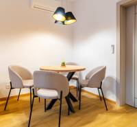 Jemná jídelna v 3-pokojovém bytě s kulatým stolem a křesly, podlaha s dřevěným dekorem.