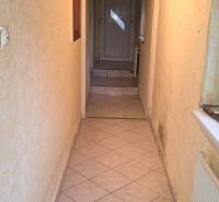 Úzká interiérová chodba s dlažbou a dřevěným stropem v rodinném domě.