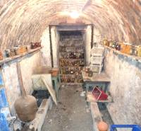 Podzemní sklep v rodinném domě s cihlovým stropem a policemi se zavařeninami.