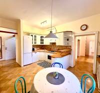 Kuchyně ve 4-pokojovém bytě s podlahou s dřevěným dekorem a jídelním stolem.