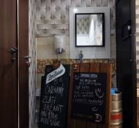 Interiérové obchodní prostory se zrcadlem, umyvadlem a tabulemi s nabídkou nápojů.