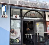 Obchodní prostory v Šali s velkým oknem, dřevěným dekorem a bílými židlemi.