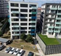 Pohled na moderní bytové domy se zaparkovanými auty na ulici Jégého, Bratislava - Nivy.