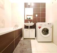 Koupelna v 2-pokojovém bytě s pračkou, vanou a umyvadlem.