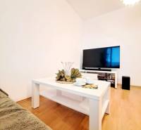 Obývací pokoj v 2-pokojovém bytě s podlahou s dřevěným dekorem a bílým stolem.