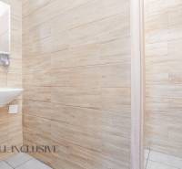 Interiér kanceláře s umyvadlem, dřevěnými stěnami a otevřenými dveřmi.