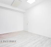 Interiér s bílými stěnami a podlahou s dřevěným dekorem v kanceláři.