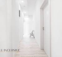 Světlá chodba s dřevěnou podlahou a židlí v kanceláři.