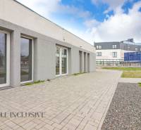 Na ulici Vajanského, vedle obchodní prostory s moderní architekturou a zpevněnými chodníky.