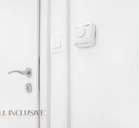 Bílá stěna s termostatem a klikou v kanceláři.