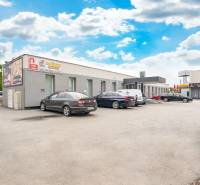 Budovy na Clementisových Sadech v Galantě s zaparkovanými vozidly u kanceláří.