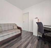 Pohovka a pracovní stůl v rodinném domě s podlahou s dřevěným dekorem.