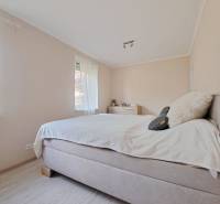 Světlá ložnice v rodinném domě s pohodlnou postelí a podlahou s dřevěným dekorem.