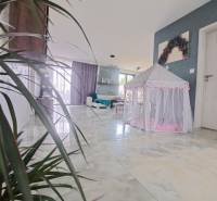 Interiér rodinného domu se stanem pro děti na lesklé podlaze a rostlinami.