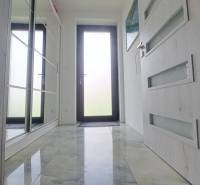 Interiér rodinného domu s lesklou keramickou podlahou a skleněnými dveřmi.