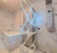 Koupelna s moderním sprchovým koutem, vanou a designovým osvětlením v rodinném domě.