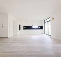 Prostorná kuchyně s černým obkladem a podlahou s dřevěným dekorem v rodinném domě.